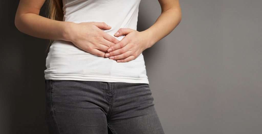 a young woman with bellyache or menstrual cramps holding her stomach