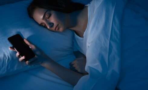 Woman sleeping with smartphone in bed