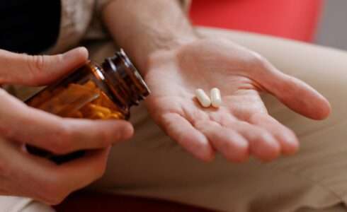 Close up of man hands taking medical supplements.