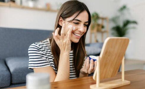 Smiling young pretty woman applying natural skin cream at her face for healthy skin in Meridian Idaho